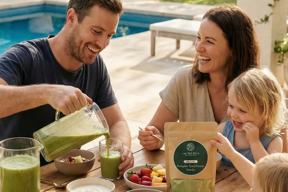 A family enjoying a green smoothie breakfast outdoors with a pouch of van Mel & Co. Organic Pumpkin Seed Protein Powder on the table